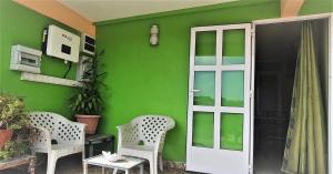 托舵道斯金贝壳公寓式酒店的绿色房子,带两把椅子和一扇门