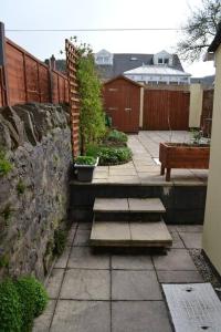 卡菲利Entire 3 bedroom house near Caerphilly station的庭院设有台阶、石墙和围栏