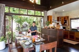 湄南海滩The Emerald Hill Beach Villa的站在厨房里一边吃饭的人