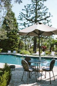 代森扎诺-德尔加达Hotel Piccola Vela的游泳池旁配有遮阳伞的桌椅