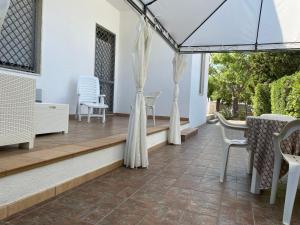 托雷拉皮罗Casa Alieta的庭院配有白色的椅子和带窗帘的桌子。