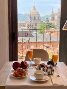 圣洛伦索-德埃斯科里亚尔圣洛伦索套房酒店的一张桌子,上面摆放着食品和饮料,享有城市美景