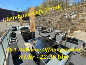 AntweilerGästehaus - Café Frank的阳台设有玻璃桌椅和砖墙