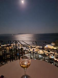 圣加利尼Iro Hotel的坐在海边的桌子上喝一杯葡萄酒