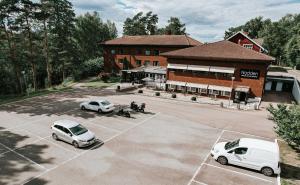 RamnäsNadden Hotell & Konferens的两辆白色汽车停在大楼前的停车场