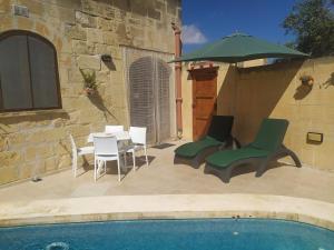 萨奈特Gozo Rustic Farmhouse with stunning views and swimming pool的庭院配有桌椅和遮阳伞。