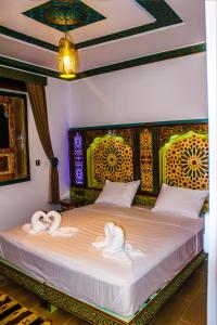 舍夫沙万Riad Azemmat的一间卧室,床上配有两只天鹅的毛巾