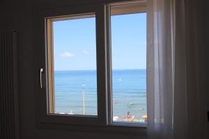 切法卢B&B Le Suites di Costanza的窗户享有海滩和大海的景致。