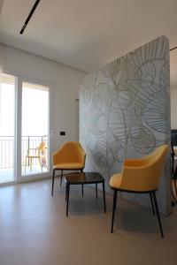 切法卢B&B Le Suites di Costanza的墙上的房间里摆放着两把椅子和一张桌子