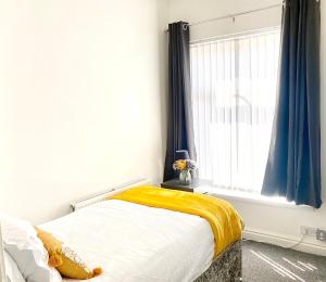 曼彻斯特Cosy Cheerful 2 Beds Near Piccadilly, Etihad Stadium Sleeps upto 5的一间卧室配有一张带黄色毯子和窗户的床