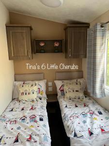 考斯6 Little Cherubs Holiday Home的一间卧室配有两张单人床和白色床单