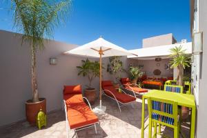 马拉喀什Riad Mylaya的庭院配有橙色椅子和遮阳伞。