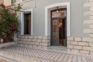 萨摩斯Villa Samos - Renovated stone villa with private pool- 2 min from the sea!的白色建筑的前门,有植物