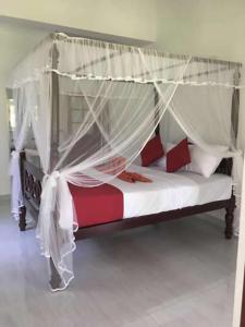 陶尔佩Lush Green Villa的卧室配有带白色和红色枕头的天蓬床。