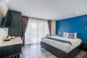 华欣Anchan Hotel & Spa的一间卧室设有一张大床和蓝色的墙壁