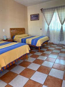 特基斯基亚潘Hotel El Mirador的客房设有两张床,铺有瓷砖地板。