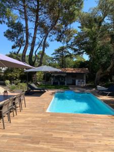 索尔特奥瑟戈尔Villa de charme avec piscine à 500m des plages的一个带椅子和遮阳伞的游泳池以及一座房子