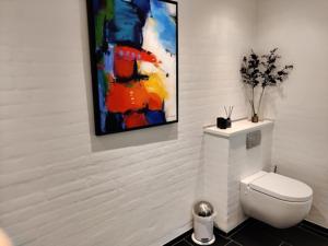 海宁Værelser i midtbyen的一间带卫生间的浴室和墙上的绘画