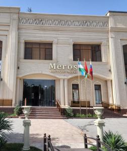 撒马尔罕Meros Boutique Hotel的一座梅蒂斯建筑,前面有两面旗帜