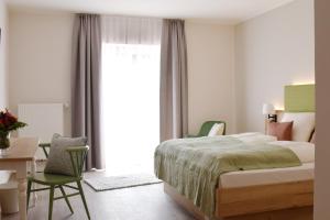 BasthorstLandhaus Hamester - Hotel & Restaurant - neu eröffnet September 2022的一间卧室配有一张床、一张书桌和一个窗户。