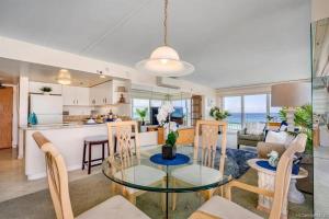 檀香山Ilikai #1743 Panoramic views on Waikiki Beach的厨房以及带玻璃桌和椅子的客厅。