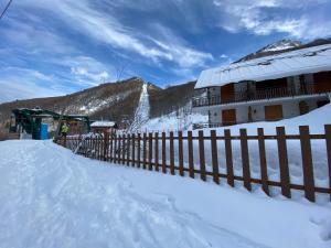 利莫内皮埃蒙特La Baita Limone Riserva Bianca Ski-in Ski-out Seggiovia Morel 1的雪中带围栏的建筑