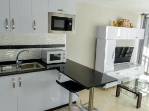 莫甘Apartamentos Guadalupe Gran Canaria Puerto Rico的厨房配有白色橱柜和黑色台面