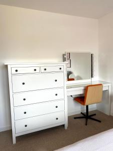 蒙特罗斯Bright 2-bedroom apartment with parking in Montrose的白色梳妆台,配有镜子和椅子