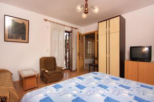 瓦比尼科Apartment Vrbnik 5301b的一间卧室配有一张床、一把椅子和电视。