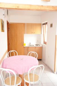 奈维斯Apartment Njivice 5398a的厨房配有粉红色的桌子和椅子
