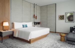 曼谷曼谷金普顿玫兰酒店 - an IHG Hotel的卧室配有一张白色大床和一把椅子