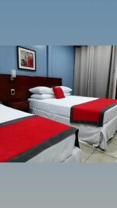 TigreHotel Boutique Malibu Los Sueños的两张位于酒店客房的床,配有红色和白色床单