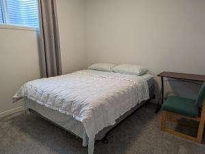 卡尔加里Livingston Howse Haven - A simple & cozy private two-bedroom basement suite with free parking的一间卧室配有一张床、一张桌子和一把椅子