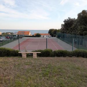 波尔尼克Loralistudios, Maison en bord de mer的前面设有网球场和长凳