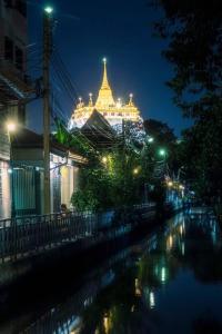曼谷Non House Hostel บ้านนอนโฮสเทล的夜间有灯光的建筑物,有河流