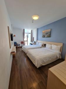 大叻彦安百花酒店的一间卧室设有两张床和蓝色的墙壁