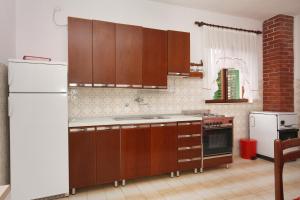 苏佩塔尔Apartments with WiFi Supetar, Brac - 5667的厨房配有木制橱柜和白色冰箱。