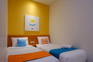 日惹Sans Hotel Pippo Yogyakarta by RedDoorz的黄色墙壁客房中的两张单人床