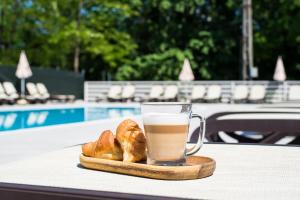 百乐费利克斯HOTEL VITAL的一杯咖啡和面包在游泳池附近的桌子上