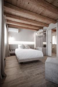 瓦尔多比亚德内Locanda MaMaGiò的卧室设有白色大床和木制天花板。