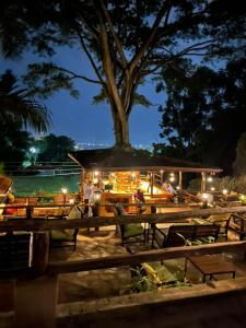 坎帕拉Kampala Forest Resort - KFR Lodge的一间晚上带桌子和树的餐厅