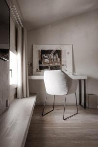 瓦尔多比亚德内Locanda MaMaGiò的一张白色椅子,坐在带书桌的房间