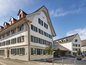 穆里CASPAR Swiss Quality Hotel的一座带绿色百叶窗的大型白色建筑