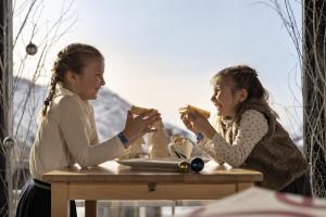 阿沃里亚兹Belambra Clubs Avoriaz - Les Cimes du Soleil的两个女孩坐在桌子旁吃着食物