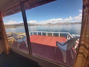 普诺Titicaca Utama Lodge Perú的船上的甲板上配有两把椅子和一张桌子