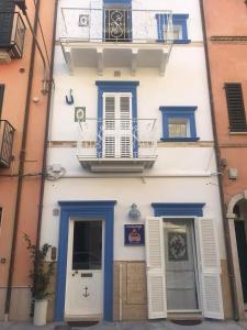 圣贝内代托-德尔特龙托Acasadelpescatore的白色的建筑,设有蓝色的门和阳台
