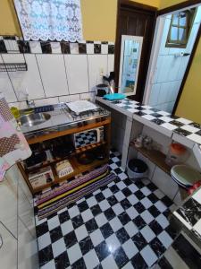 蜜岛Morada das Flores Chalé/Kitnet的厨房铺有黑白的格子地板。