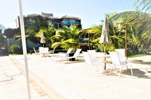 阿奎拉兹BEACH PARK PALM - COBERTURA Luxo的庭院配有白色的桌椅和遮阳伞。