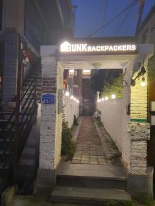 首尔Bunk Backpackers Guesthouse的带有阅读太阳灯背包手的标志的建筑物入口