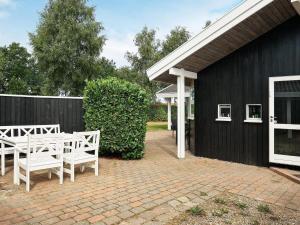 奥特鲁普Holiday home Otterup XVIII的一座带白色椅子的庭院和一座黑色的建筑